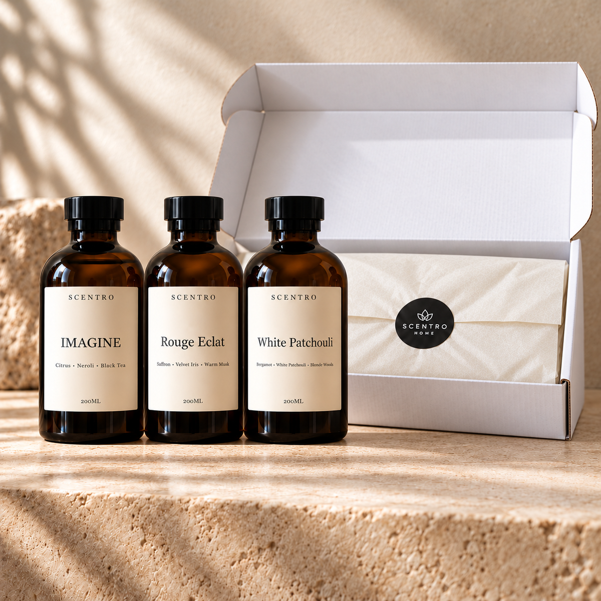 Scentro Home three-bottle diffuser oil bundle beside a larger white postal box with cream tissue and black Scentro Home seal.